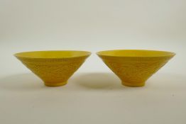A pair of Chinese yellow ground porcelain conical bowls with raised dragon decoration, seal mark