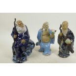 A Chinese, Shiwan style, mud men figure of a pilgrim seated on a rock, 8½" high, together with two