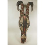 An African carved and painted wood horned animal head mask, 24½" long