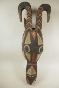 An African carved and painted wood horned animal head mask, 24½" long