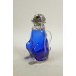 A silver plated and blue glass claret jug in the form of a monkey, 8" high, crack to handle