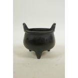 A Chinese bronze two handled censer on tripod supports, with dark patina, impressed mark to base,