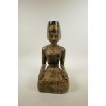 An Indian carved and painted wooden seated figure, 13½" high