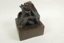 A Chinese bronze seal cast with an entwined dragon, 5" square, 6½" high