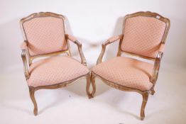 A pair of giltwood open armchairs with shaped backs and carved decoration