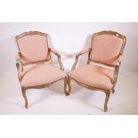 A pair of giltwood open armchairs with shaped backs and carved decoration