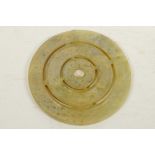 A Chinese hardstone pi disc carved as three concentric rings with dimpled decoration, 4¾" diameter