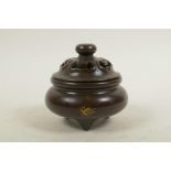 A Chinese bronze censer and cover on tripod supports, with gilt splash patina, impressed four