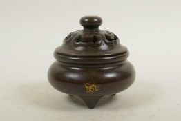 A Chinese bronze censer and cover on tripod supports, with gilt splash patina, impressed four