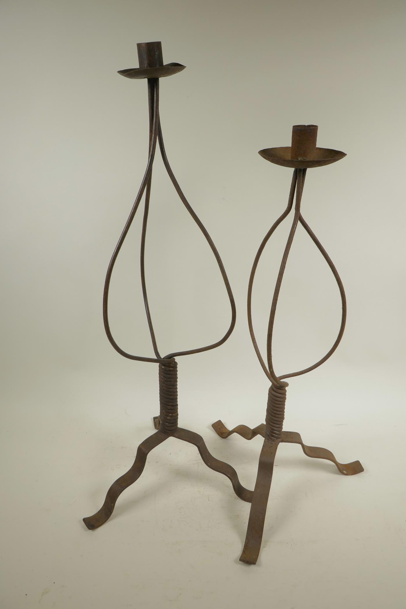 A wrought iron candlestick on tripod base, 24½" high, and another similar