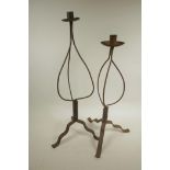 A wrought iron candlestick on tripod base, 24½" high, and another similar