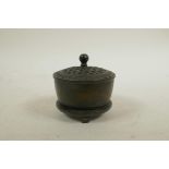 A Chinese bronze cylinder censer on tripod supports with a pierced cover, impressed mark to base, 3"
