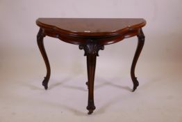 A C19th walnut shaped top fold over card table with carved cabriole legs and scrolled feet, 39" x