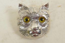 A silver brooch in the form of a cat's head with glass eyes, 1¼" long