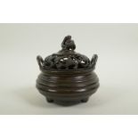A Chinese bronze censer of ribbed form with two phoenix eye handles, a pierced cover decorated