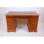 A Victorian style yew wood pedestal desk with eight drawers and inset gilt tooled leather top,