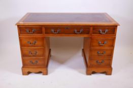 A Victorian style yew wood pedestal desk with eight drawers and inset gilt tooled leather top,