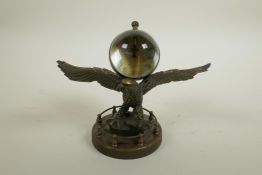 A brass and glass ball desk clock mounted on the back of an eagle, 7" wide, 5½" high