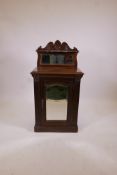 A C19th walnut music cabinet with carved, raised mirrored back, mirrored panel door and reeded