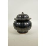 A Chinese treacle glazed pottery pot and cover in the form of a gourd, 8" high