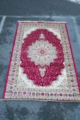 A Kashmiri red ground rug with an unique floral medallion design, 61½" x 91"
