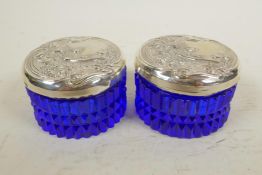 Two blue glass dressing table jars with sterling silver lids embossed with Art Nouveau designs,