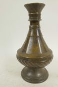 An antique bronze vase with slender neck and whorled and ring turned decoration, possibly Persian,