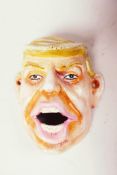 A wall mounted iron bottle opener cast as a caricature of Donald Trump, 4" long