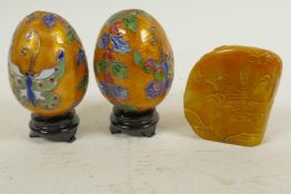 A pair of Chinese decorative cloisonne eggs on wooden stands, together with a carved soapstone