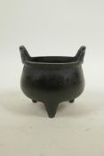 A Chinese bronze two handled censer on tripod supports, with dark patina, impressed mark to base,