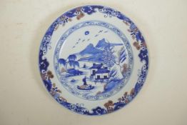 A Chinese blue and white porcelain cabinet plate decorated with a riverside landscape, with red