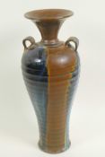 A Chinese stoneware baluster vase with rib formed body and two loop handles, drip glazed in brown