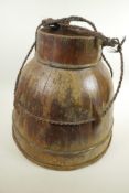 An Oriental wooden water jar of bound stave construction, with rope carry handle, 14½" high, 16"