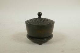 A Chinese bronze cylinder censer on tripod supports with a pierced cover, impressed mark to base, 3"