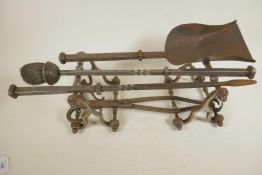 A pair of turned steel fire dogs together with a four piece set of blacksmith wrought fire tools,