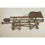 A pair of turned steel fire dogs together with a four piece set of blacksmith wrought fire tools,