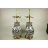 A pair of Chinese famille verte porcelain table lamps of bulbous form decorated with figures in a