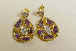 A pair of silver gilt pendant earrings set with uncut diamonds encircled by uncut rubies, 1" drop