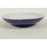 A Chinese porcelain shallow dish with dark blue glaze calligraphy marks to base, 6" diameter