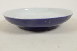 A Chinese porcelain shallow dish with dark blue glaze calligraphy marks to base, 6" diameter