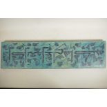 A Persian turquoise glazed four tile plaque decorated with an Eastern inscription, 8" x 31½"