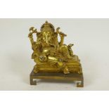 A gilt bronze figure of Lord Ganesh reclining on a couch, 5" long, on a key pattern plinth