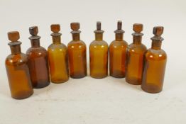Eight antique amber glass chemist bottles with stoppers, 4½" high