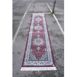 A Turkish red ground deep pile runner decorated with floral medallions on a blue field with cream