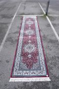 A Turkish red ground deep pile runner decorated with floral medallions on a blue field with cream
