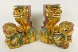 A pair of carved giltwood fo dogs with hawks on their backs, 10" high