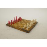 A leather bound travel chess set with turned and dyed bone pieces, one pawn missing, 7" x 7"