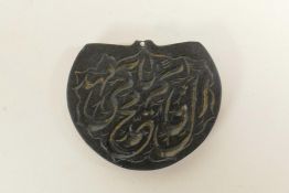 An Islamic carved blackstone pendant with calligraphy decoration, 2" x 1½"