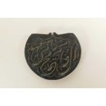 An Islamic carved blackstone pendant with calligraphy decoration, 2" x 1½"