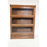 An oak Globe Wernicke four section bookcase with drawer base and three glass door shelves, 47" high,